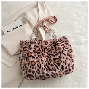 Detail of pink leopard faux fur tote bag with metal chain strap on white blazer background