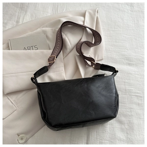 Detail of minimalist black crossbody bag with a patterned geometric wide shoulder strap