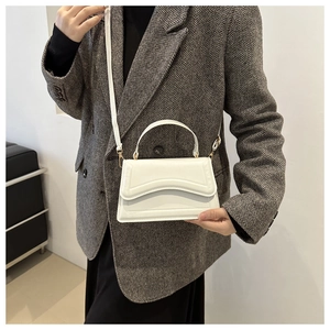 Detail of white wave quilted crossbody bag with golden hardware and top handle strap