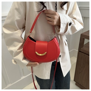 Detail of red crescent shoulder bag with gold hardware buckle and slender leather strap