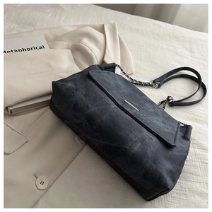Detail of dark grey washed canvas shoulder bag with silver chain and leather strap
