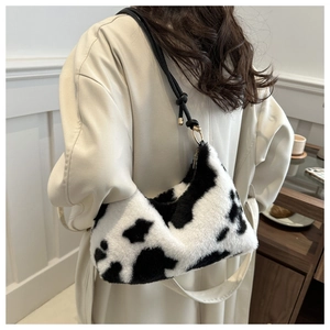 Detail of plush cow print shoulder bag with black strap and golden metal ring
