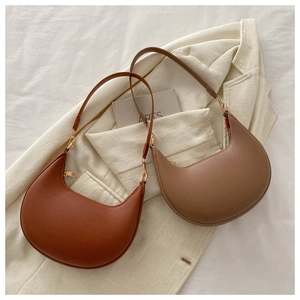 Detail of minimalist crescent hobo bags in terracotta and khaki with smooth PU leather finish