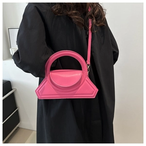 Vibrant pink geometric crossbody bag with top handle styled on a black coat outfit