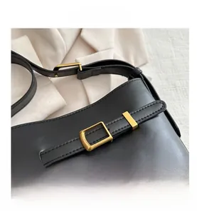 Detail of adjustable gold buckle and fine stitching on a black matte leather bucket bag
