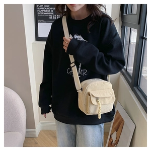 Detail of cream corduroy crossbody bag showing adjustable strap and texture in use