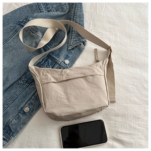 Detail of minimalist beige nylon crossbody bag with wide strap and front pocket