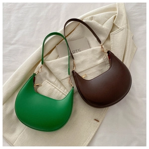 Close-up of green and brown PU leather crescent bags with gold metal hardware and stitching