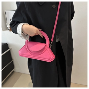 Detail of vibrant pink geometric trapezoid handbag with integrated circular handle and strap