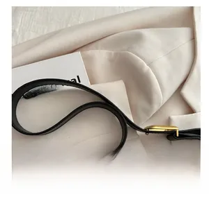 Detail of adjustable black leather shoulder strap with elegant gold metal buckle on a blazer