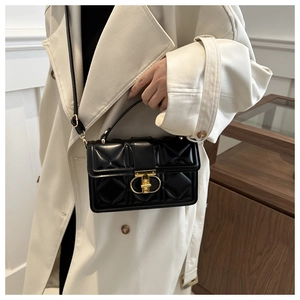 Detail of black quilted PU leather crossbody bag with elegant gold clasp and metal ring