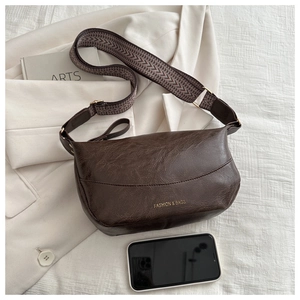 Detail of dark coffee PU leather bag with wide pattern strap and phone for size reference