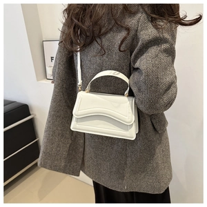 Close-up of white minimalist wave-cut handbag paired with a grey herringbone wool coat