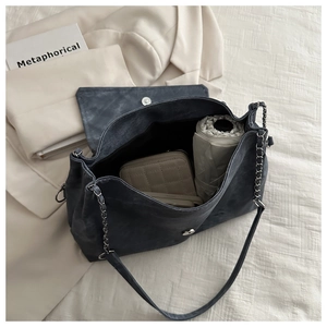 Interior storage view of grey denim shoulder bag with chain strap on white blazer