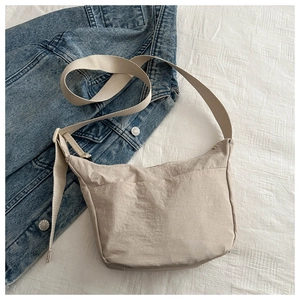 Detail of light khaki nylon crossbody bag featuring an adjustable strap and large front pocket