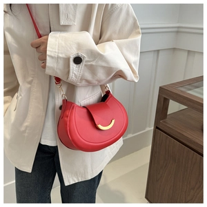 Detail of red crescent shoulder bag with golden metal hardware and matte leather finish