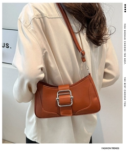 Détail du sac sous l'aisselle en similicuir orange brun avec grande boucle argentée
