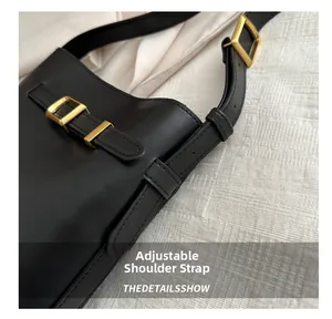 Detail of adjustable shoulder strap with gold buckle on black leather handbag