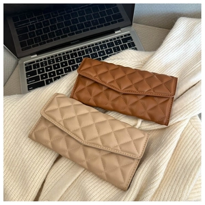 Detailed view of quilted leather long wallets in brown and beige colors with a luxury texture