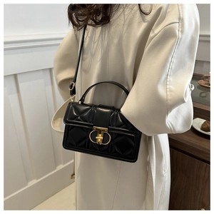 Close-up of black quilted PU leather crossbody bag with gold metal clasp on a model