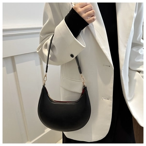 Detail of black crescent shoulder bag with gold hardware and contrast red lining