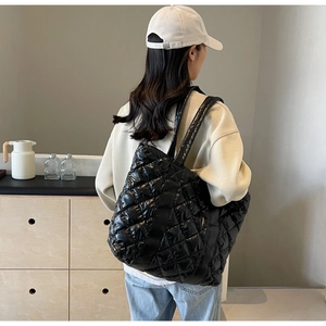 Close-up of black glossy quilted tote bag with diamond stitching and high-shine finish