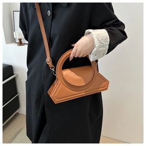 Brown geometric crossbody bag with a large circular handle shown on model in minimalist style