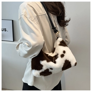 Close-up of plush cow print underarm bag with black leather strap and gold metal hardware