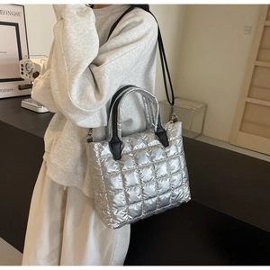 Sac cabas argenté matelassé avec anses noires porté par un mannequin en studio