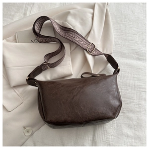Close-up of vintage dark brown faux leather bag with wide geometric woven shoulder strap
