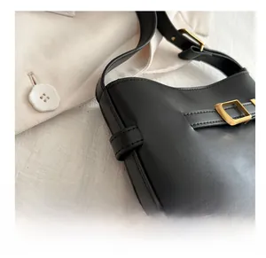 Detail of black PU leather shoulder bag featuring smooth finish and gold square buckle
