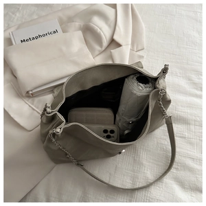 Macro detail of spacious interior in beige faux leather chain shoulder bag with phone