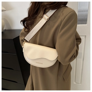 Détail du sac bandoulière demi-lune crème avec large sangle en tissu et boucles dorées
