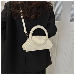 Close-up of stylish white geometric crossbody bag with unique round handle on black suit