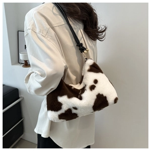 Detail of plush cow print shoulder bag with knotted black strap and gold metal hardware