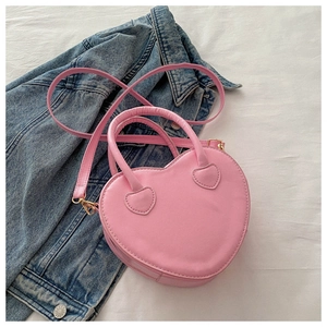 Detailed view of pink heart-shaped bag with gold hardware and pink shoulder strap