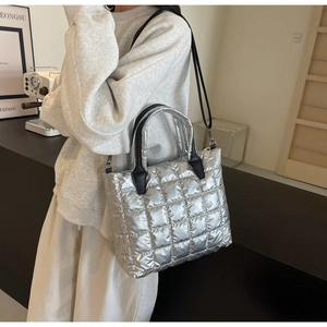 Sac à main argenté métallisé porté par un mannequin dans un intérieur minimaliste