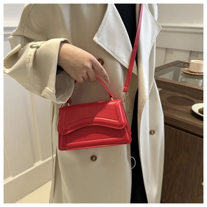 Detail of red leather mini handbag with wavy embossed texture and elegant top handle