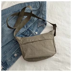 Detail of army green nylon messenger bag with adjustable strap on denim background