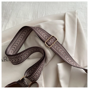 Detail of adjustable woven shoulder strap with retro geometric patterns and gold buckle