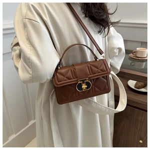 Detail of brown quilted PU leather crossbody bag with golden twist-lock and top handle