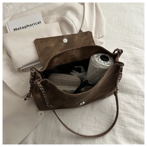Detail of dark brown suede shoulder bag with magnetic buckle and chain strap