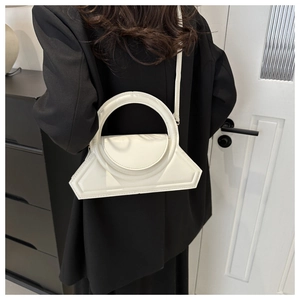 Detail showing white minimalist bag with a large circular handle and shiny leather texture