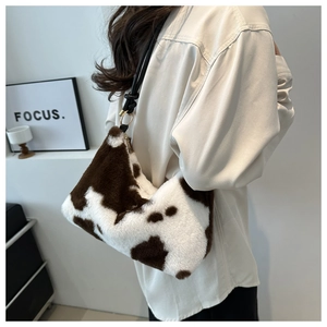 Detail of plush cow print shoulder bag with soft faux fur texture and gold hardware