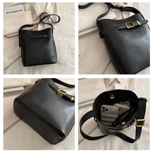 Detail view of black matte leather bucket bag showing gold hardware and spacious interior