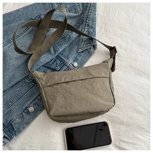 Detailed view of an olive green crescent crossbody bag styled with a blue denim jacket