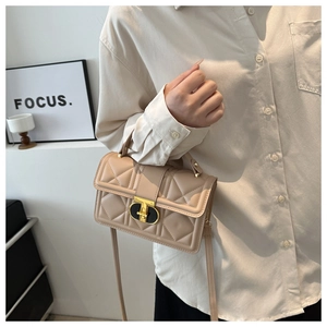 Detail of beige quilted PU crossbody bag featuring a gold-tone oval metal twist lock