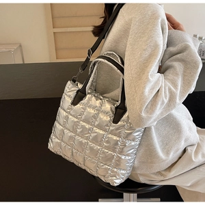 Detail view of silver quilted crossbody bag with puffer texture and black straps