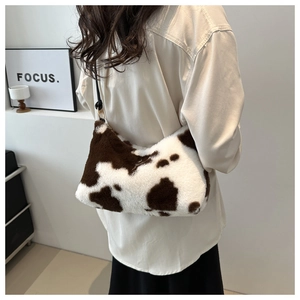 Detail shot of a plush cow print shoulder bag worn by a model in a minimalist setting