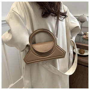Brown geometric crossbody bag with unique metal ring handle shown on a model